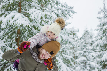 Young bearded man with little girl have fun in snowy forest in winter. 