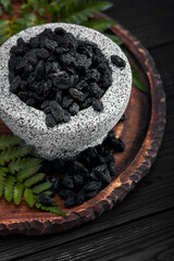 Close up of black raisins in a stone bowl, close up, dark background