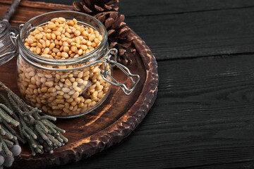 Pine nuts in a glass dish on a dark background with nuts scattered around