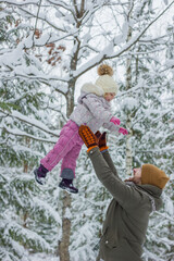 Handsome young dad and his little cute daughter are having fun outdoor in winter. Enjoying spending time together in snowy forest.