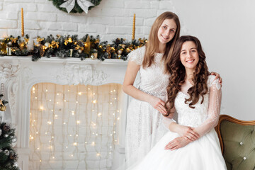 Beautiful bride in luxury wedding dress and pretty bridesmaid in dresse in decorated christmas...