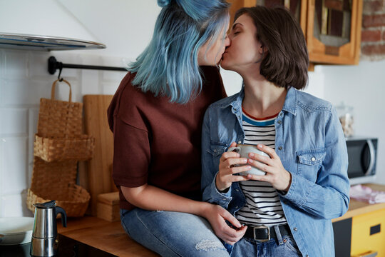 Lesbian couple kissing in the kitchen in the morning