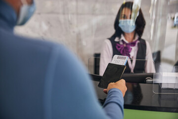 Passenger showing his travel documents to a dark-haired airport employee