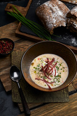 Traditional Italian soup with barley and bresaola on old wooden background. Selective focus. Dark tone.
