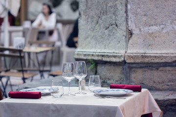 Empty outdoor restaurant table for two. Summer terrace cafe. Blurred background.