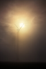Silhouette of a wind turbine on a foggy morning in the light of the rising sun