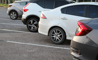 Closeup of rear or back side of brown car and other cars parking in parking lot in the evening. 