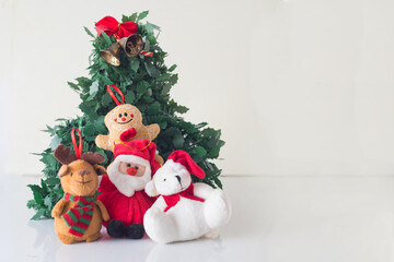 Some dolls like reindeer bears cookies and christmas decorations next to santa claus have fun around a christmas tree in the prosperity of the new year in white background