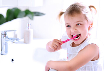 Child cleaning teeth with toothbrush,little girl in bathroom dental hygiene concept.