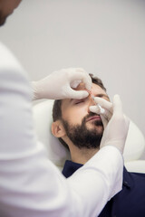 Young man getting beauty facial injections in salon. Beautician makes cosmetic injection into the male patient frown lines. Beauty injections, mesotherapy, revitalization and rejuvenation