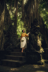 Girl in the Monkey Forest. Bali. Girl in a white dress on the nature. Traditional Balinese bag. Travel.