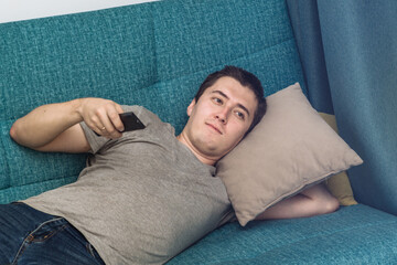 one young man is watching TV lying on the sofa. relax on the weekend, be lazy