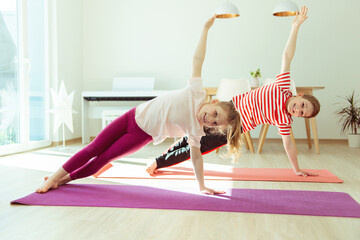 Happy children making yoga at home dueing coronavirus quarantine