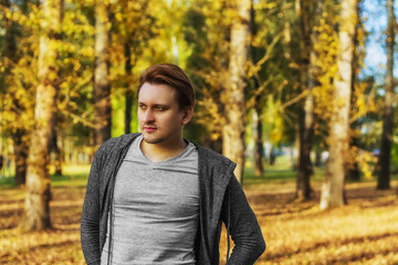 Attractive young man stands in park