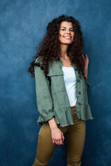 Naklejka premium young pretty woman with curly brunette hair posing cheerful on blue background, lifestyle people concept