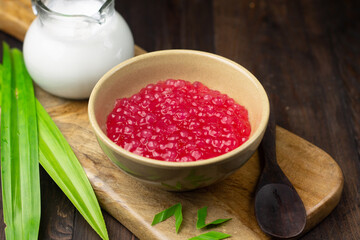 Bubur Mutiara Merah Putih or Sago pearls porridge, Indonesian popular traditional dessert made from sago pearls and coconut milk, served on ceramic bowl, garnished with pandan leaves.