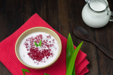Bubur Mutiara Merah Putih or Sago pearls porridge, Indonesian popular traditional dessert made from sago pearls and coconut milk, served on ceramic bowl, garnished with pandan leaves.