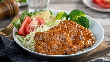 Delicious juicy pork chops with vegetable and fruit salad in a plate.