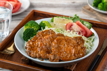 Delicious juicy pork chops with vegetable and fruit salad in a plate.