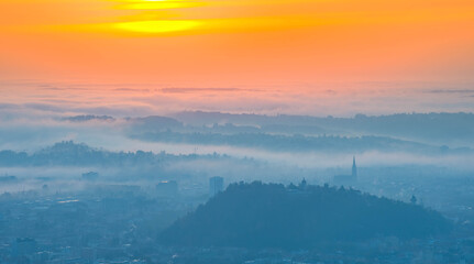 Amazing foggy sunrise over the city of Graz with Schlossberg hill and Church of the Sacred Heart of...