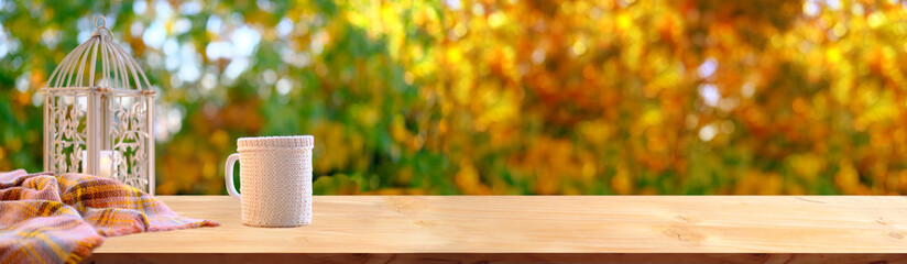 wooden table in the garden, tea, coffee in a mug, a candle is burning in a candlestick, long panorama, the concept of an outdoor tea party, good weather, a cozy autumn mood
