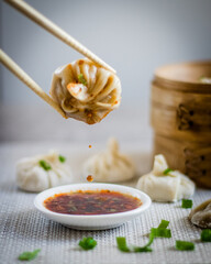 Dumpling dipped in chili sauce on a light background.