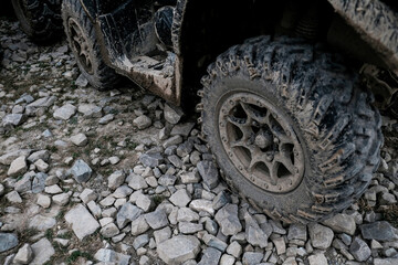 Fototapeta na wymiar Closeup view of dirty muddy quad bike tire. Off-road extreme transportation for adventurous lifestyle. Dirt on tires after riding in the mud. Adventure travel with renting 4x4 vehicles in summer.