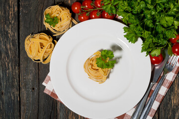 table setting with white plate, pasta and vegetables on a wooden table