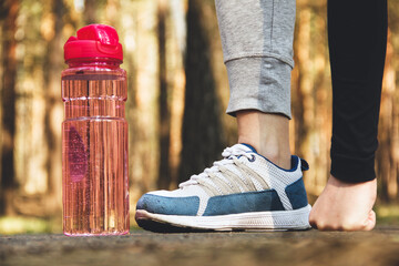 Sports shoes and sports bottle close up on forest background