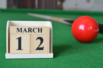 March 12, number cube with balls on snooker table, sport background.