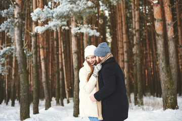 Lovely smiling Couples hugs each other in a snowy pine forest outdoor