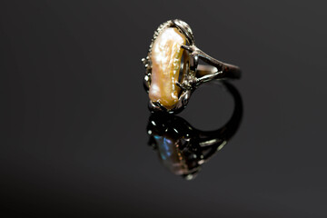 Old ring with amber close up macro shot on reflecting dark background, space for text.