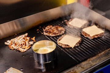 Burgers are grilled at the diner. Diner kitchen. Grill for burgers. Cheeseburgers are grilled.