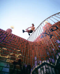 young white caucasian boy doing parkour in the city jumping fence stunts by the looks deadly...