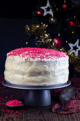 Red velvet cake with cream cheese frosting and red sugar decoration, christmas decoration on background,  vertical