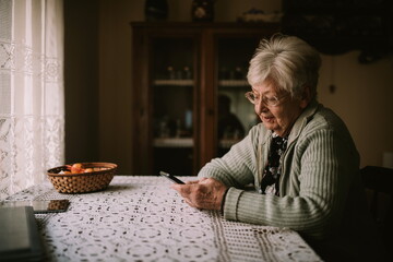 Cute senior caucasian  grandmother sitting at a table in the house and writing a message to her family during quarantine COVID - 19 coronavirus