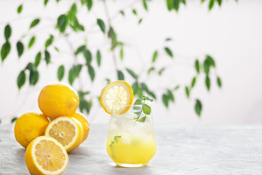 Citrus iced lemonade in the glass with lemon slice and mint leaves decoration on marble table on natural background