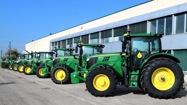 Basiliano, Italy. March 2 2019. Row Of Brand New John Deere Tractors Outside The Store Of Local Consortium, Exhibition Of Latest Agricultural Machinery.