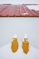 Yellow propane gas tanks by a shed in snow. Red roof. South Iceland.