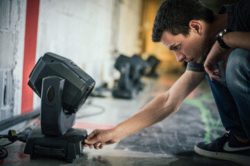 Theater lighting technician electric engineer adjusting focus of lighting elements backstage....
