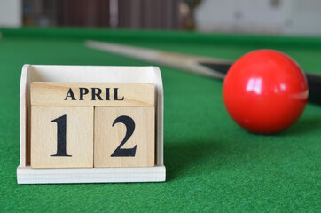 April 12, number cube with balls on snooker table, sport background.