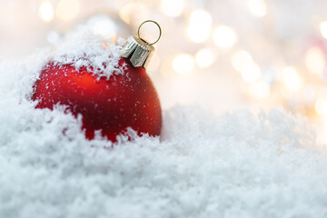 Czerwona bombka świąteczna, dekoracja na boże narodzenie na śnieżnym podłożu.