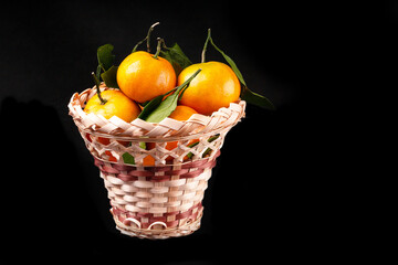 Citrus Ripe orange tangerine with green leaves isolated on a black background organic food full basket