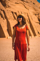 A young tourist in red dress visiting the Temple of Nefertari near Abu Simbel in southern Egypt in Nubia next to Lake Nasser. Temple of Pharaoh Ramses II, travel lifestyle