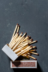 Open matchbox and scattered matchsticks on dark background, top view. Copy space.