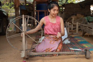 Young Asian woman spinning cotton thread