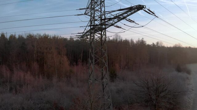 Rise crane up aerial shot, showcasing high-voltage pole in the middle of public infrastructure for electricity distribution in Germany, amidst a foggy misty forest