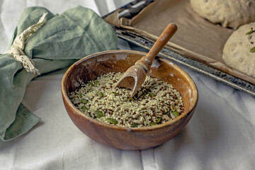 Cereal mixture of sesame seeds, pumpkin seeds, sunflower seeds in a wooden bowl with a scoop. A mixture of seeds for baking sprinkling bread on a white background. Natural food concept