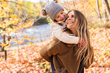 Little girl and her mother playing in the autumn park