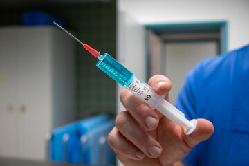 syringe filled with blue liquid are in one hand